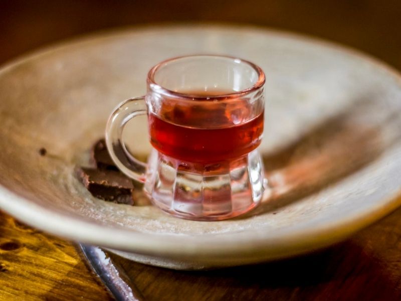 small cup of red colored liquor called pox from mexico | what to buy in merida souvenirs