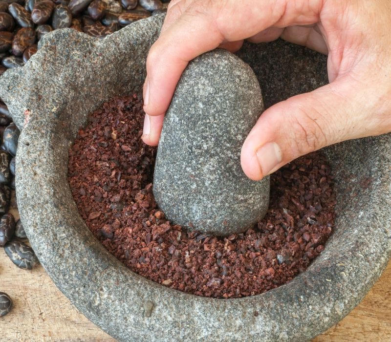woman grinding coco beans during Merida cooking classes